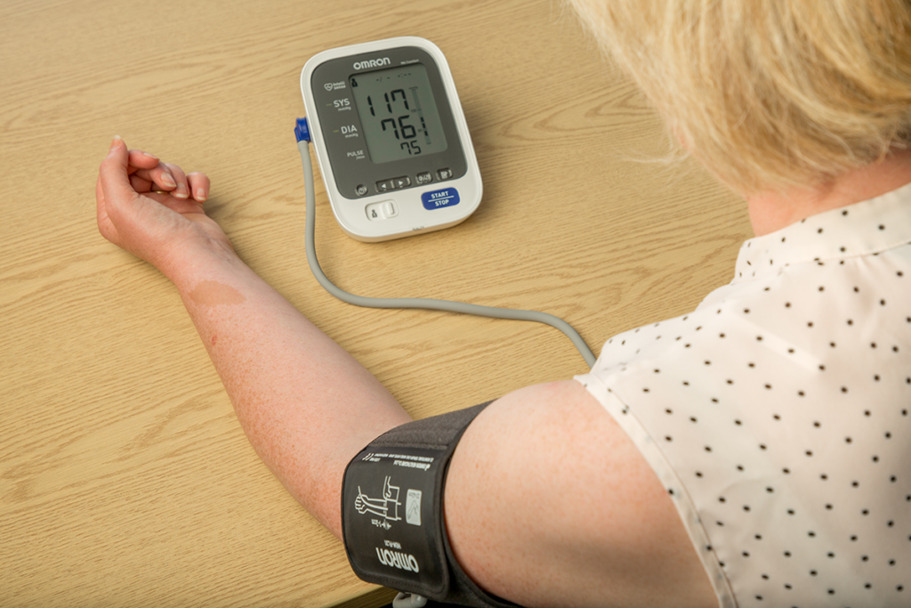Female taking her own blood pressure with home monitor