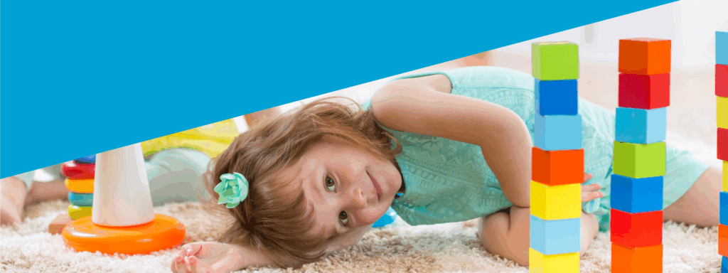 Girl leaning over on carpet, next to colourful blocks