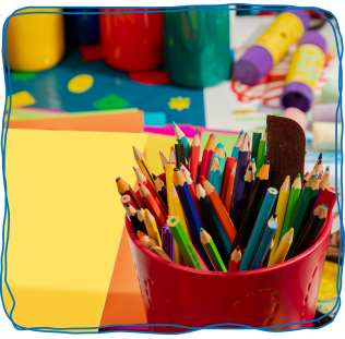 Pot of colouring pencils and colourful paper with pain, glue sticks and chalks in the background.