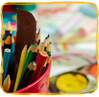 Pencils with paint and drawings in the background