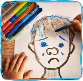 child painting a sad face picture, with tears. Colourful paints in the top left corner.