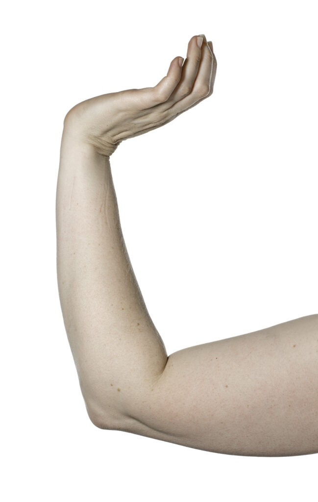 Exercise shows forearm supported on a table with hand raised and wrist bent upwards.